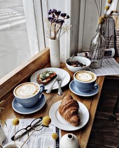 two cups of cappuccino and croissants are on the table