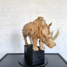 an origami rhinoceros sculpture on a black pedestal