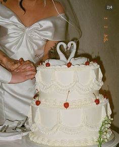 a bride and groom are cutting their wedding cake with two swans on the top tier