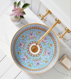 an ornate blue sink with gold faucet handles and flowers on the counter top