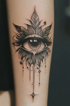 an all seeing eye tattoo on the arm and leg, with leaves around it's eyes