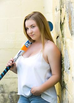 a woman holding a baseball bat next to a brick wall