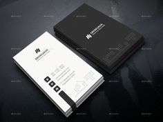 two black and white business cards on a dark surface with the letter m in the middle