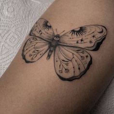 a black and white butterfly tattoo on the right thigh, with stars around it's wings