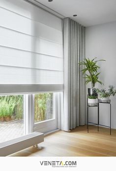 a living room with white curtains and plants in the window sill next to it