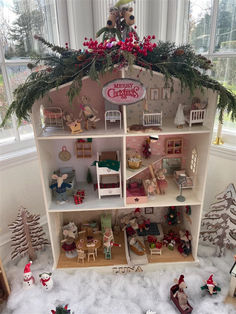 a doll house with lots of furniture and christmas decorations on the top shelf in front of a window