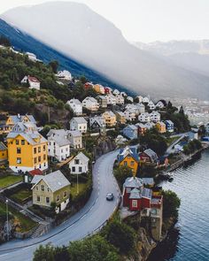 an aerial view of houses on the shore of a lake with mountains in the background