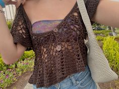 a woman is standing outside with her hand on her hip wearing a crochet top