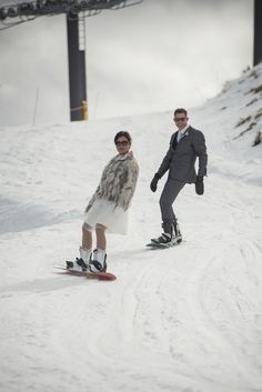 two people riding snowboards on a snowy slope