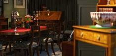 an old fashioned dining room table with chairs and vases on it's side