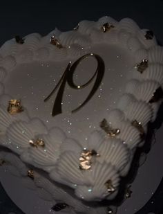 a white heart shaped cake with the number nine on it's side and gold decorations