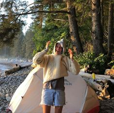 a man standing in front of a tent with his arms up and smiling at the camera