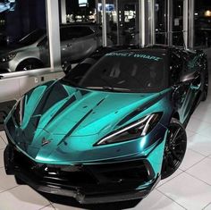 a blue sports car is parked in front of some other cars at the showroom