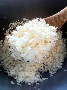 white rice is being cooked in a black bowl