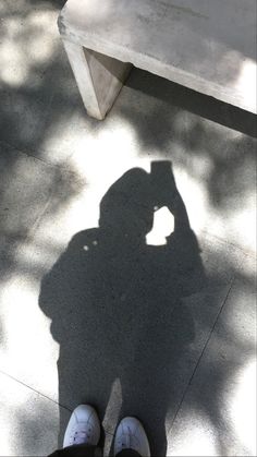 the shadow of a person standing next to a bench