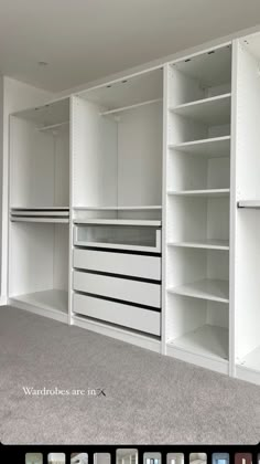 an empty room with several white shelves and drawers in the center, including two large open shelving units