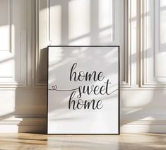 a white poster with the words home sweet home on it in front of a window