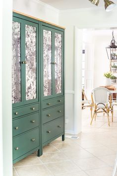 a green cabinet with glass doors is in the middle of a dining room and kitchen