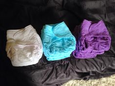 three cloth diapers sitting on top of a bed