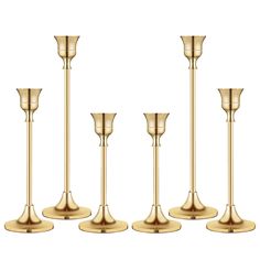 four gold candlesticks are lined up in the same row on a white background