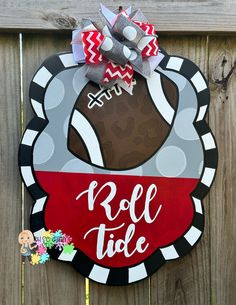 a sign that says roll tide on the side of a fence with a football in it