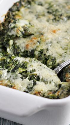 a white casserole dish with spinach and cheese in it on a table