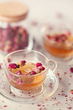 a glass tea cup filled with flowers on top of a table