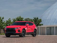 a red chevrolet suv is parked in front of a building with a large dome behind it