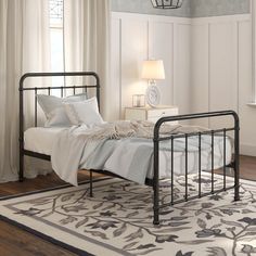 a metal bed frame in a bedroom with white walls and wood flooring, along with a rug on the floor