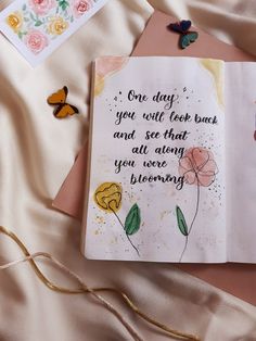 an open book with flowers and butterflies on the cover, next to some cards that say one day you will look back and see that all along you were burning