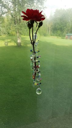 a flower hanging from the side of a window with glass beads attached to it's stems