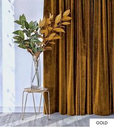 a vase with some plants in it next to a chair and curtained window sill