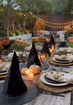 an outdoor table set for halloween with pumpkins and candles