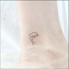 a small tattoo on the ankle of a woman's foot, depicting a dolphin