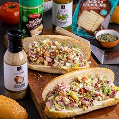 two open sandwiches sitting on top of a wooden cutting board next to other food items