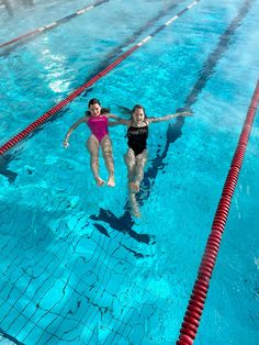 two women are in the pool and one is jumping into the water