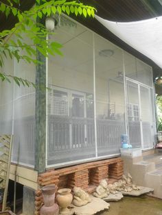 a screened porch with pots and vases sitting on the ground in front of it