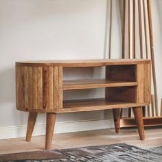 a wooden entertainment center sitting on top of a hard wood floor next to a white wall