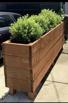 a large wooden planter sitting on the side of a road next to a car