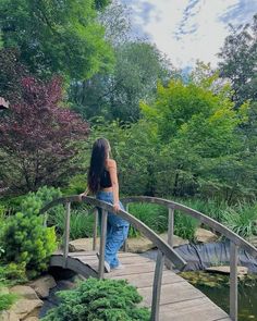 a woman standing on a bridge over a pond