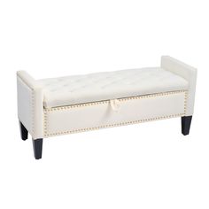 an upholstered white bench with black legs and studded trimmings on it