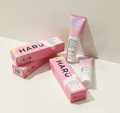 three pink boxes with the words hap next to it and two tubes containing lip balm