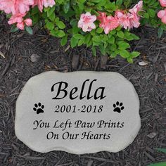 a pet memorial stone that says, bella 2011 - 2018 you left paw prints on our hearts