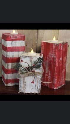 two red and white striped candles are sitting on a wooden table next to each other