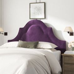 a purple headboard on a white bed in a room with two nightstands and lamps