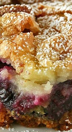 a piece of blueberry pie on a plate with powdered sugar over the top