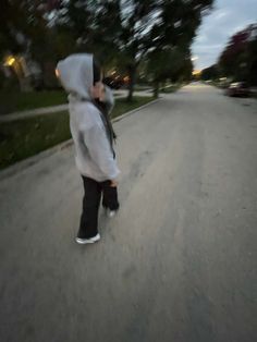 a person in a hoodie skateboarding down a street