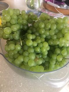 a glass bowl filled with green grapes on top of a counter