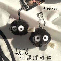 two black balls with googly eyes are hanging from a chain