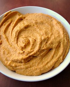 a white bowl filled with hummus on top of a wooden table